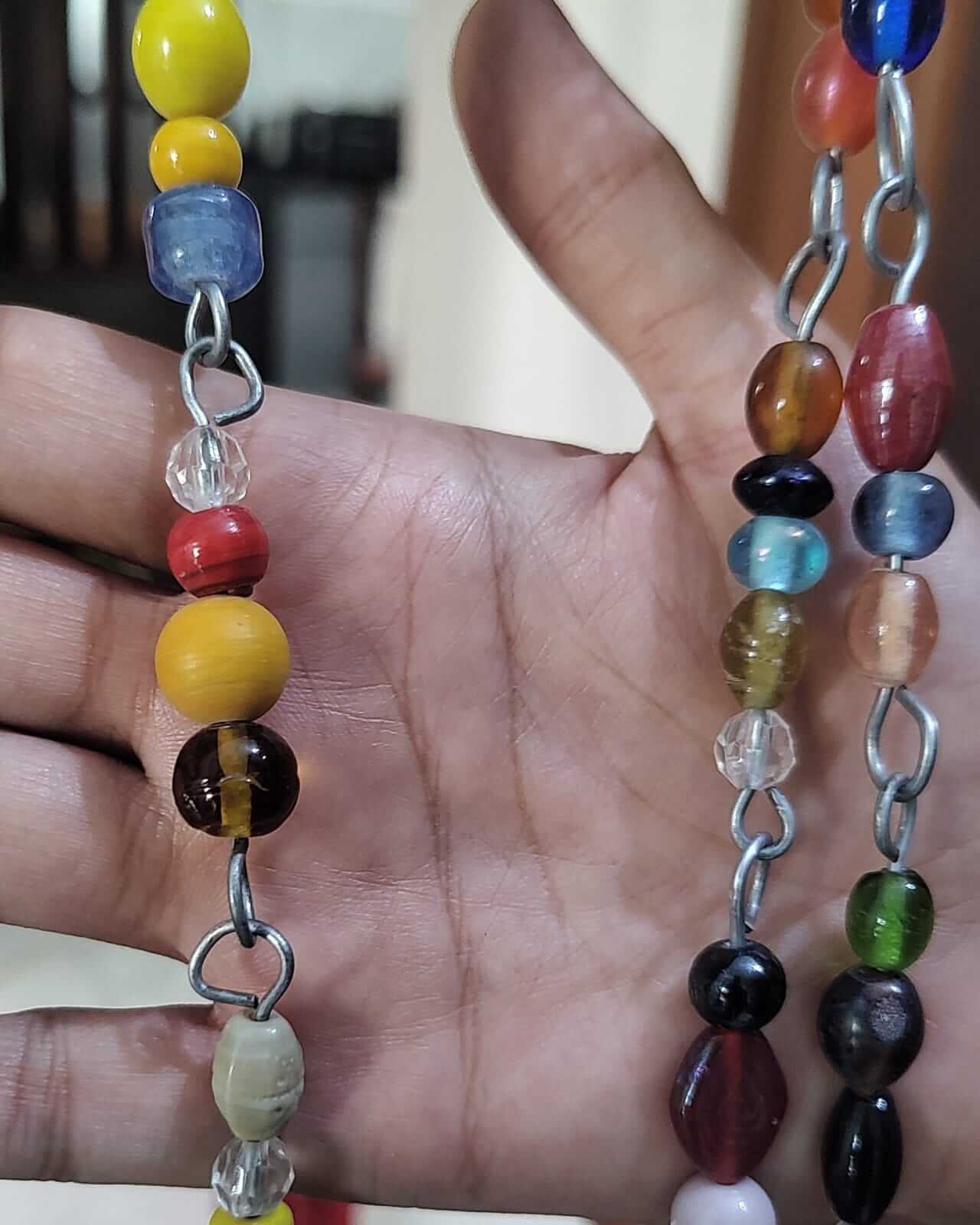 Close-up of colorful glass beaded strands showcasing vibrant hippie door beads and metal chains for bohemian decor.